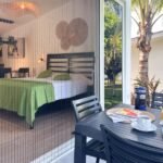bdm10 - Panama Sport Fishing Charters Hotel room seen through glass doors with a green-bedspread and a patio table set for breakfast outside, including juice, coffee, and watermelon slices.