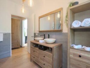 - Panama Sport Fishing Charters Wooden bathroom vanity with two vessel sinks and a large framed mirror; warm Edison bulbs and open shelving with rolled towels create a rustic-modern look.