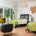 bdm14 - Panama Sport Fishing Charters Bright hotel room with two black-framed beds, lime green throws, and a sliding glass door to a tropical outdoor view.