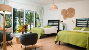 - Panama Sport Fishing Charters Bright hotel room with two black-framed beds, lime green throws, and a sliding glass door to a tropical outdoor view.