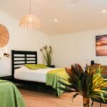 bdm15 - Panama Sport Fishing Charters Hotel room with two twin beds, green throws, wicker wall decor, and potted plants on the side.