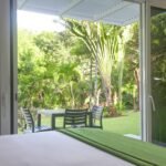 bdm16 - Panama Sport Fishing Charters View from inside looking out to a sunny backyard with a patio table and four chairs among tropical plants.