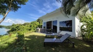- Panama Sport Fishing Charters White vacation villa with glass doors, two lounge chairs on a grassy lawn, and a lake view with tropical plants nearby?