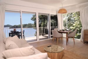 - Panama Sport Fishing Charters Bright open-plan living and dining area with large sliding glass doors to a balcony overlooking water; beige sofa, round glass coffee table, and a wooden dining table with four chairs.