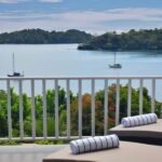 bdm22 - Panama Sport Fishing Charters Balcony with two lounge chairs and rolled white towels overlooking a calm bay with sailboats and green trees.