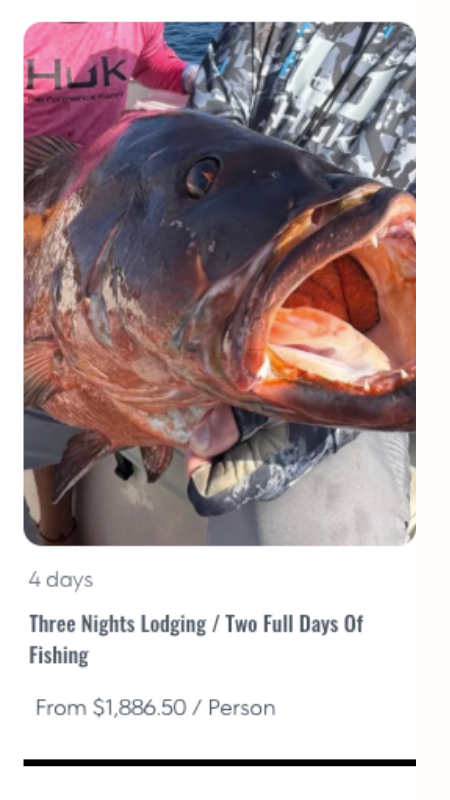 Close-up of a large fish with open mouth being held by a person wearing a pink HUK shirt on a boat.